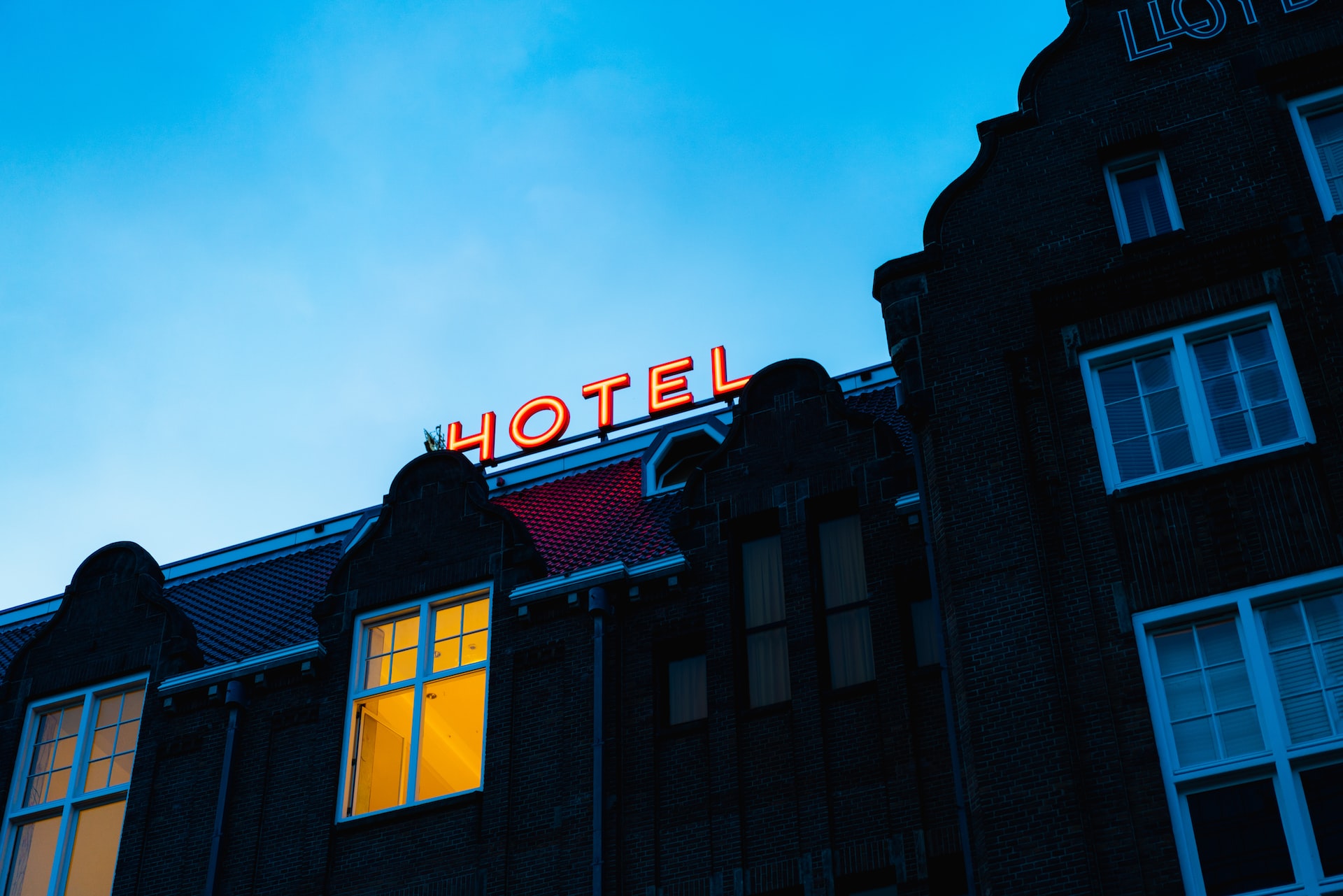 The front of a hotel, including a lit hotel sign